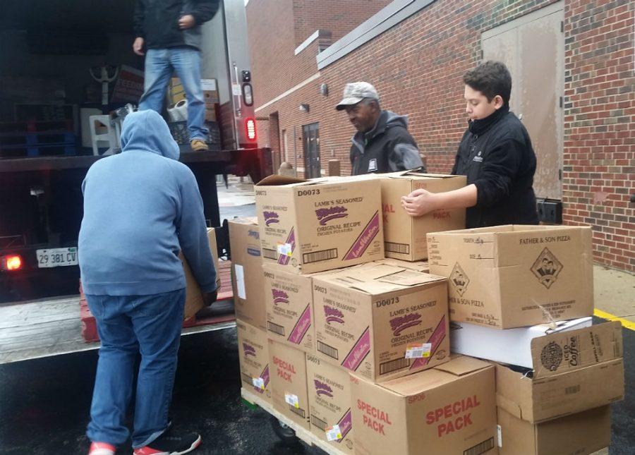Sophomore Aaron Sexton and sophomore Ibrahim Zeitoun help the Northern Illinois Food Bank staff load the cans. 
