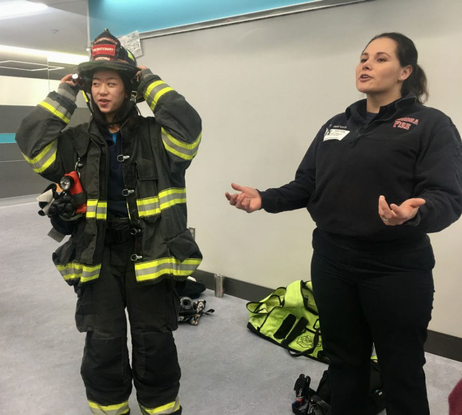 Sophomore Katie Sutherland tries on firefigther equipment brought by EMT paramedic Taylor Reeves for the HOSA panel event.