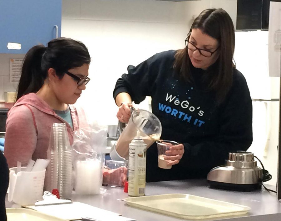Special education teacher Katie Sullivan helps student Ruby Romero prepare milkshakes for teachers.   
