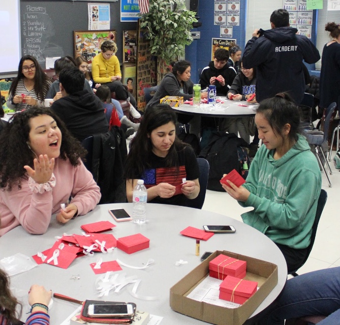 Information cards about the Yazidis will be distributed on Friday by WeGo Global members throughout the day. The white ribbon represents violence against women and support in spreading beliefs. From left, Sophomore Andrea Gutierrez, junior Ameena AlHammo, and sophomore Julia Nosky prepare the cards.
