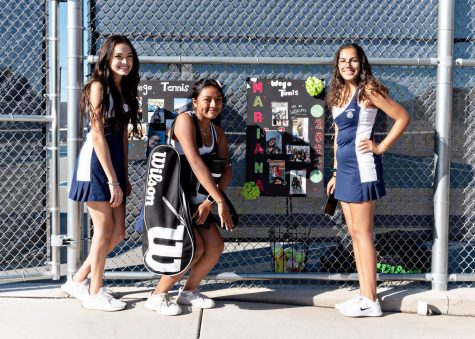 Senior members of the 2021 girls tennis team pose in front of their personalized signs on Senior Night.