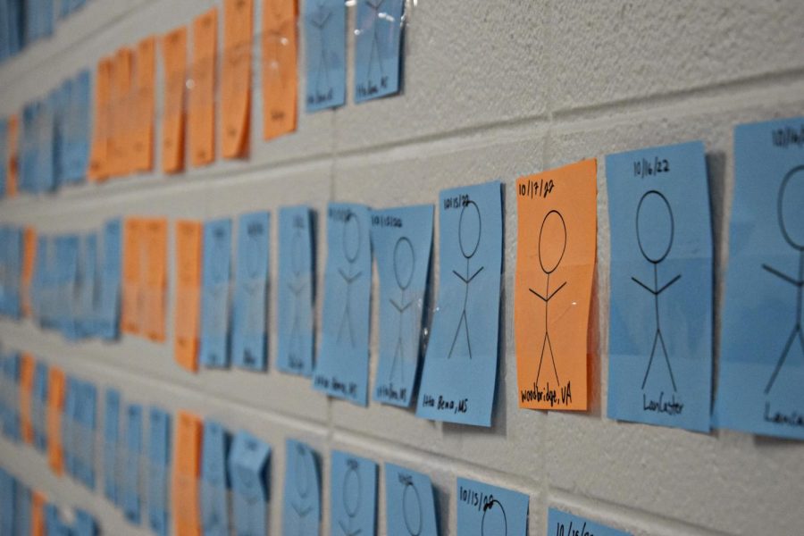 A wall in the Social Studies wing contains stick figures that represent the victims of gun violence in America. WeGo Global began adding paper squares in September.