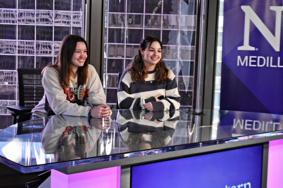 Freshmen journalism students Miley Pegg and JaNyah Villa sit in the anchors desk at Medill.