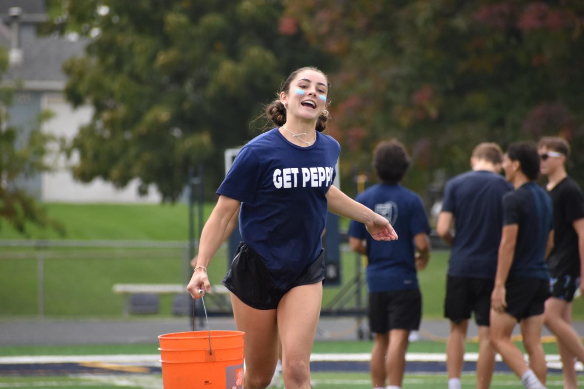 Senior Pep Club member Maggie White hauls a bucket of water down the field.