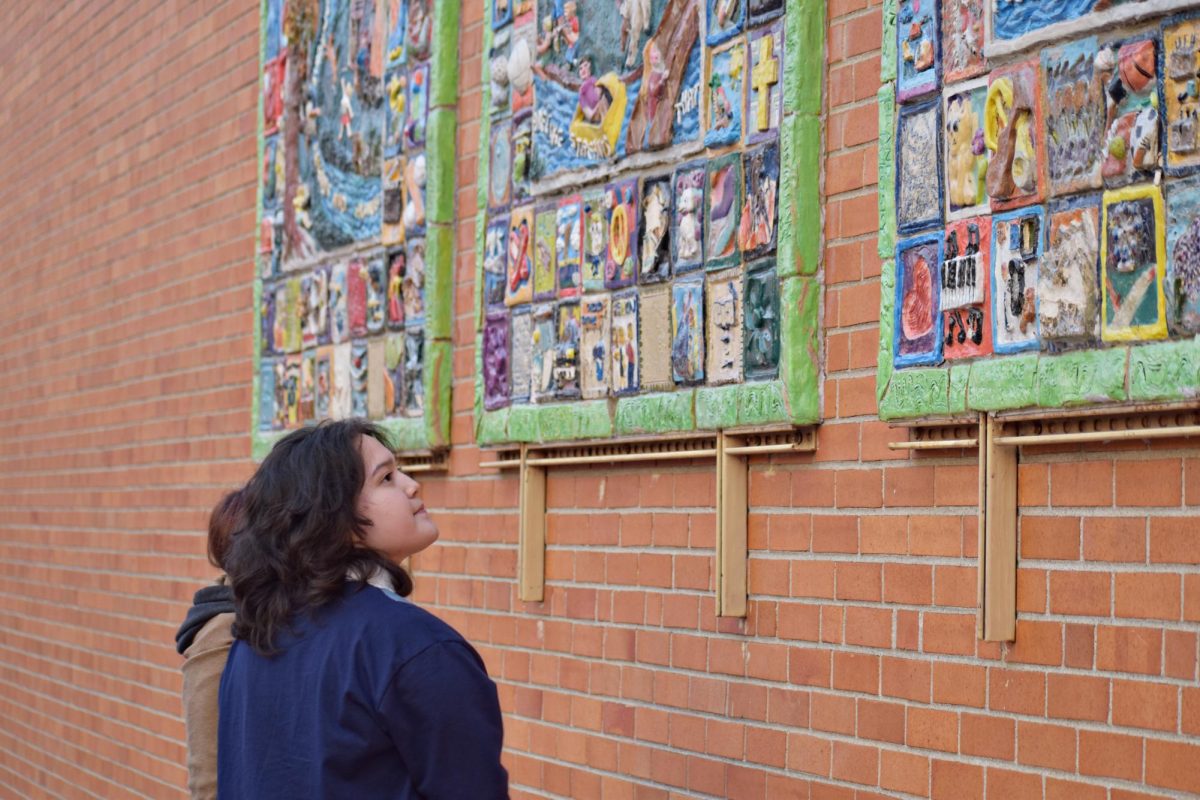 Senior Licxy Barrera examines on of the mosaics on display in Naperville. 