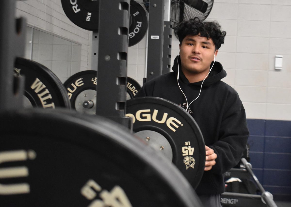 Senior Daniel Guzman changes the weights on the barbell. 