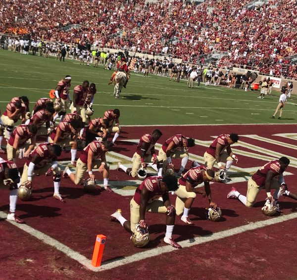 The Florida State Seminoles kneel during the National Anthem. (Royalty-free photo by Jonathan Breaker via Wikimedia Commons)
