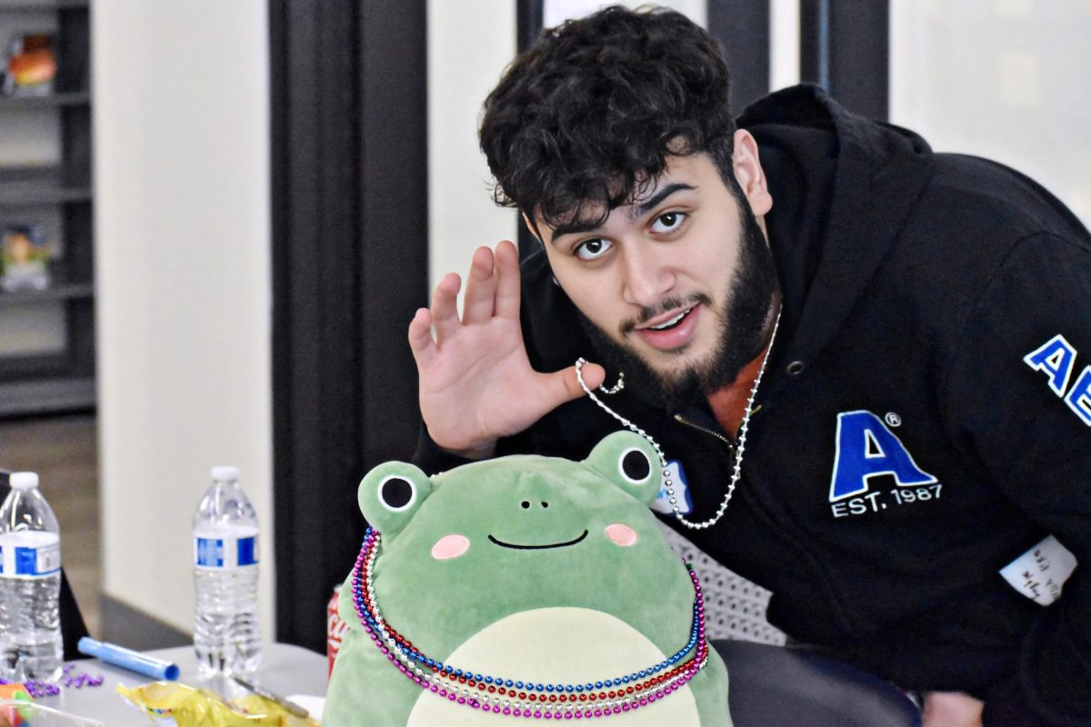 Senior and former Chronicle reporter Qssam Alwan poses with a frog squishmallow, a support stuffed animal. All while showing off his Group 1 accessory, a beaded necklace. 