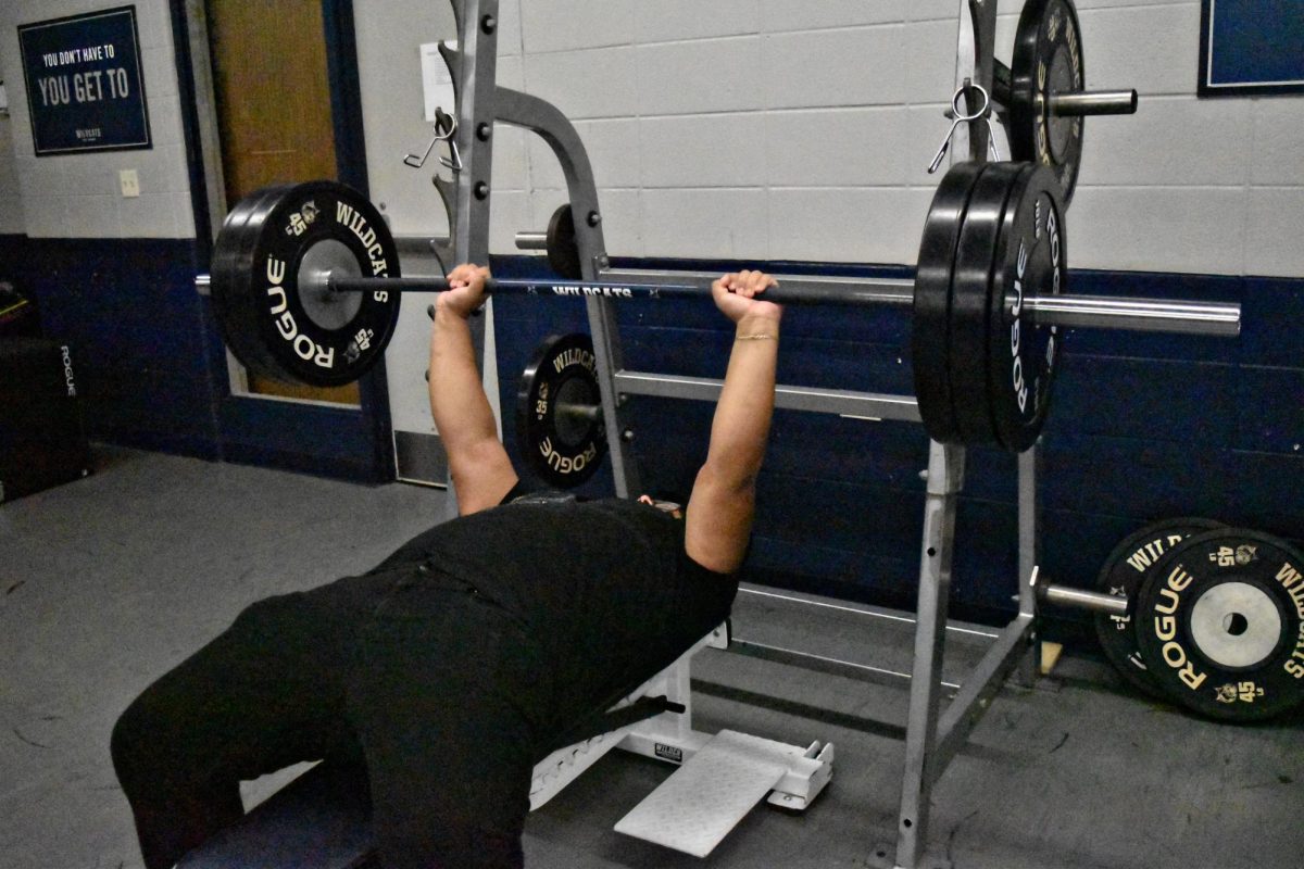 A students works on his bench press form in the weight room. 