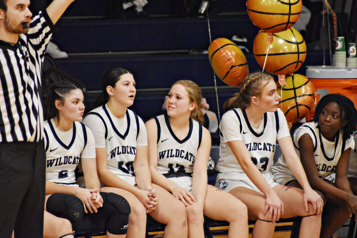 Three of the Wildcat seniors, Miranda Enochs, Sydney Bennema, and Jamie Sticha, take a few moments to catch their breath from the sideline as other players are switched in.