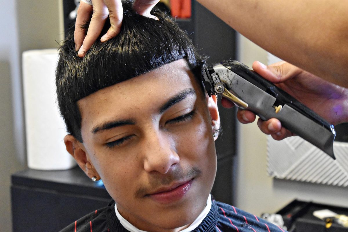 Montoya is fading his clients hair with clippers in his home-based shop.
