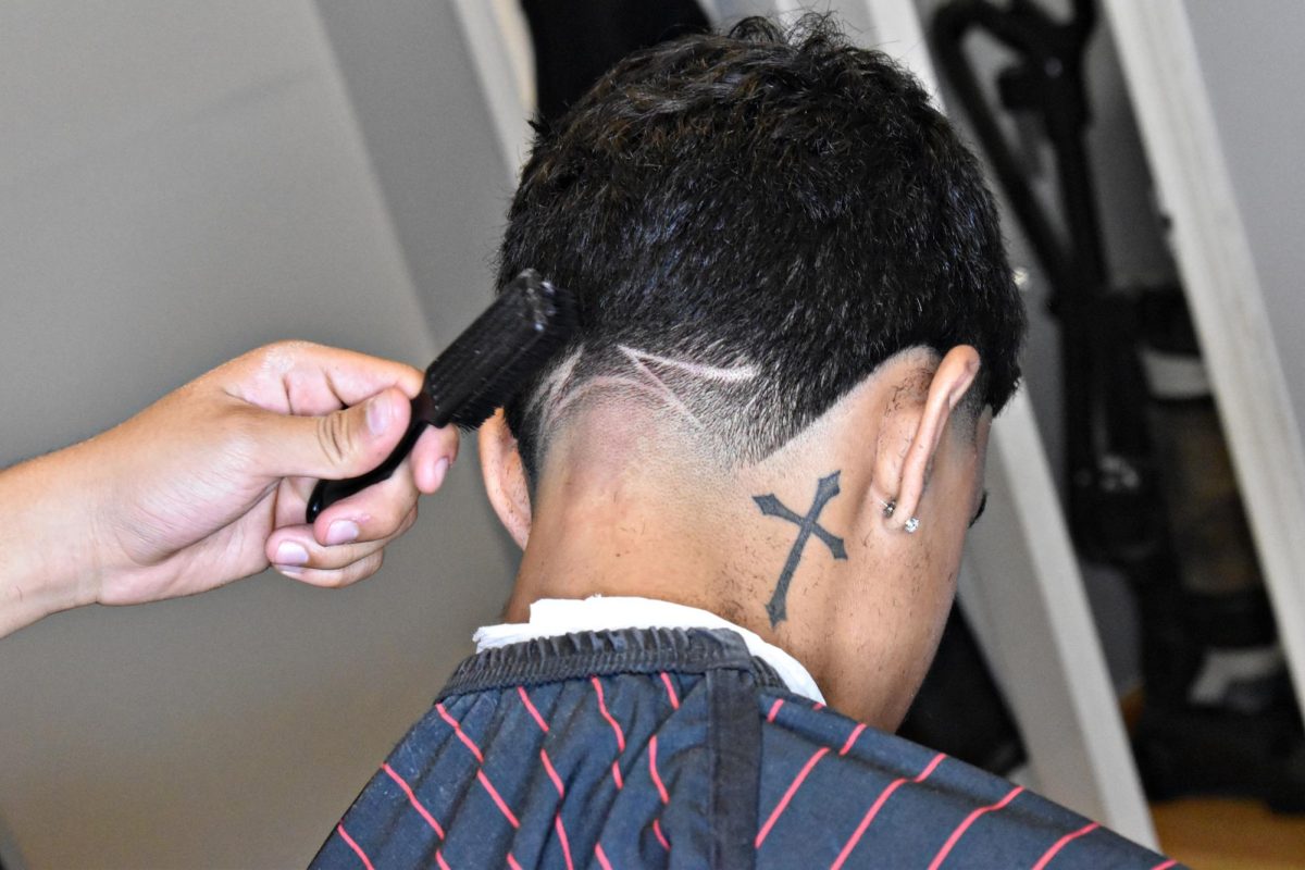 Once the cut is finished, Montoya brushes off excess hair from the clients neck, ears, and forehead.