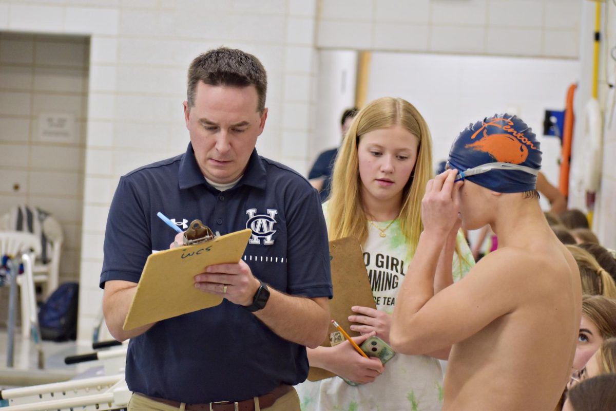 Athletic Director, Nick Parry writes on his clipboard after conversing with timekeepers.