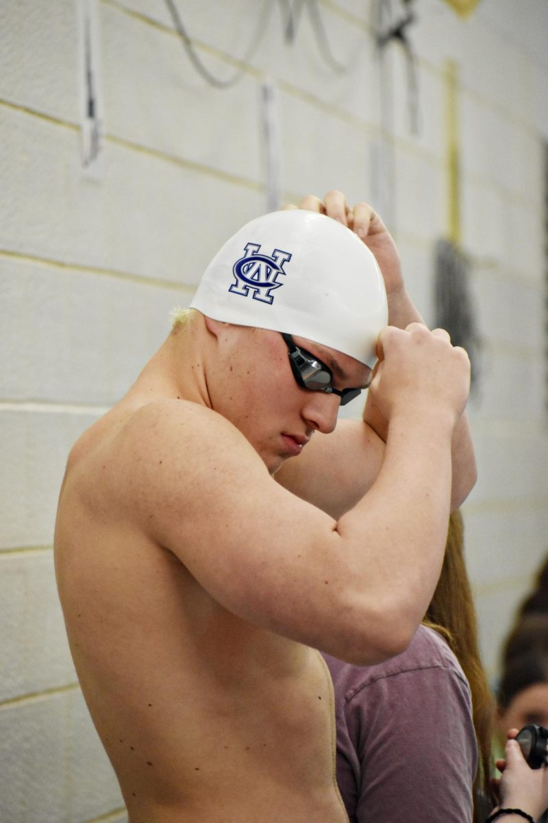 Brady Johnson fixes his white swim cap that stands out in comparison to other swimmers.