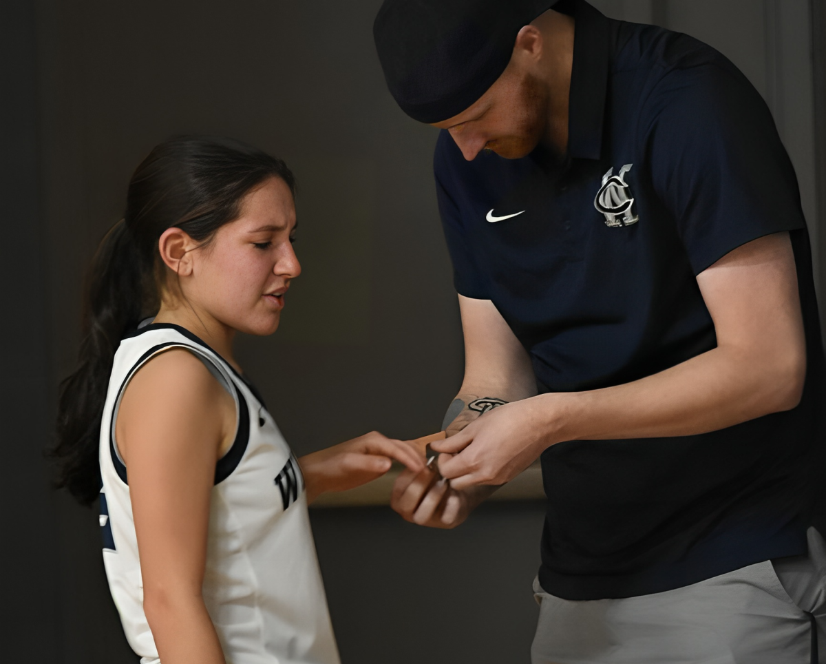 Elina Velascos finger is treated for an injury by Athletic Trainer Tom Wolfsmith during a girls basketball game. The junior was fit to play after treatment.