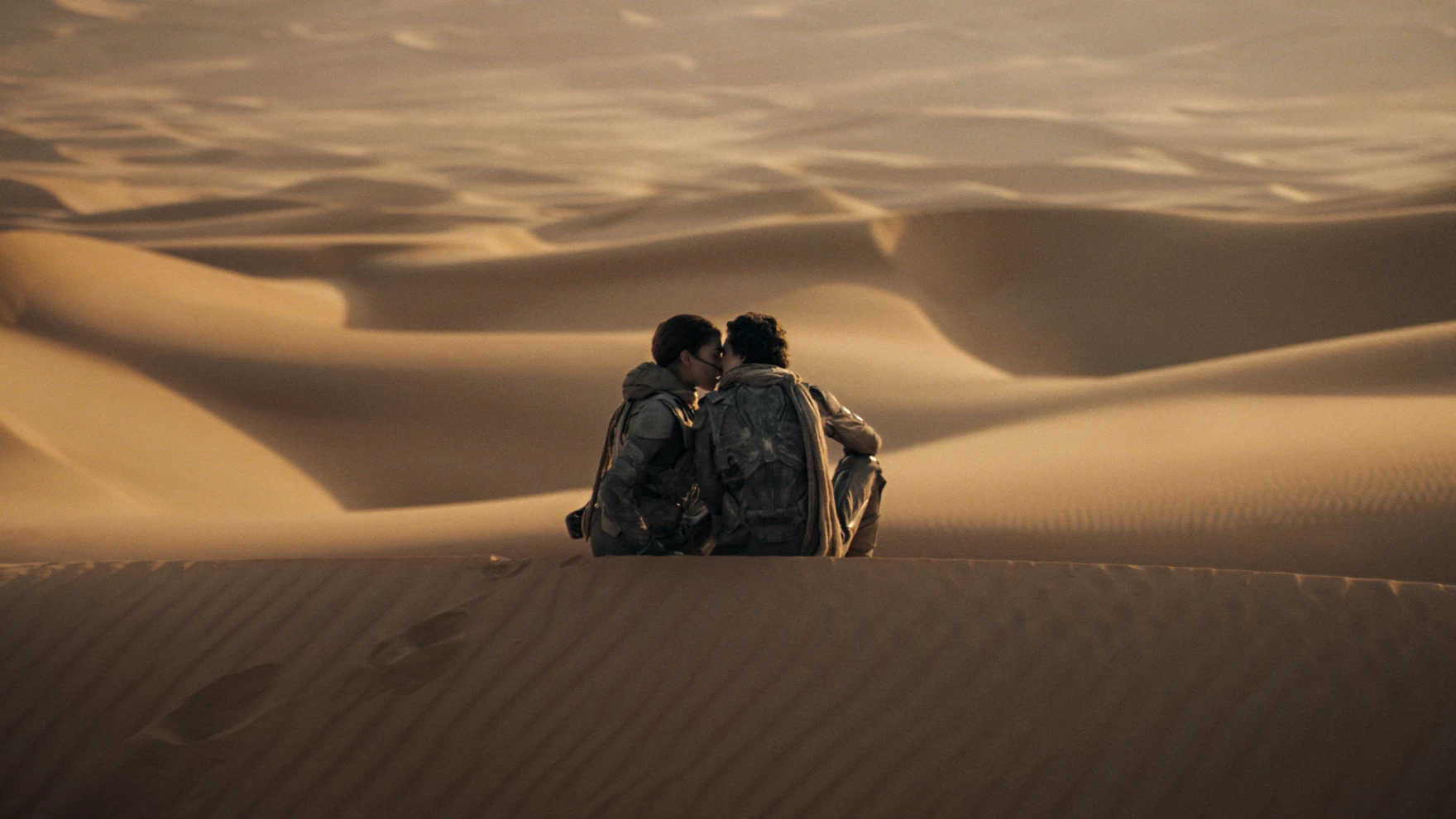 Paul Atreides (Timothee Chalamet) and Chani (Zendaya) share an intimate moment on the dunes of Arrakis (Photo courtesy of Warner Bros. Pictures).