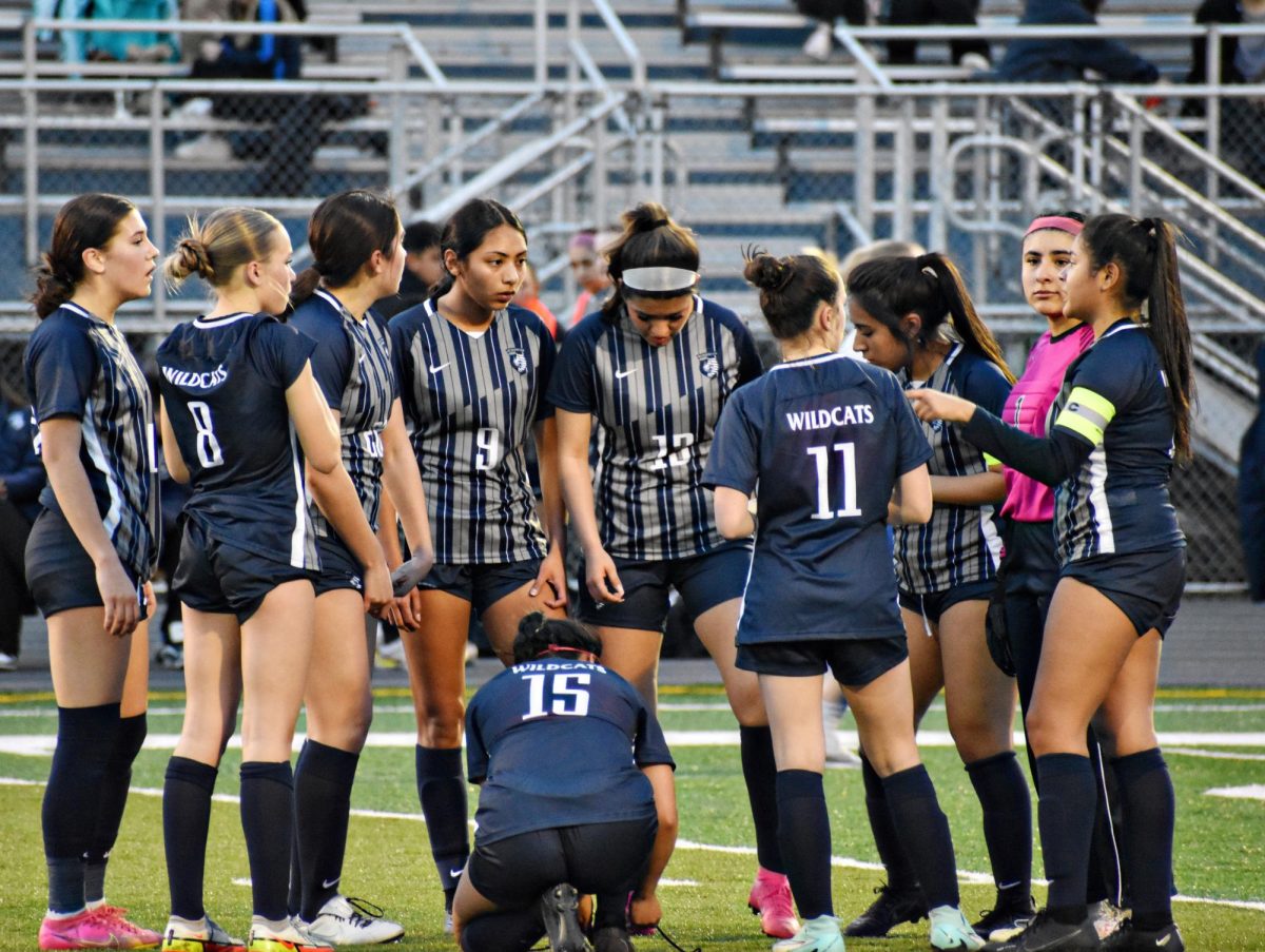 The Varsity girls soccer team huddles during a time out, strategizing their next move. 