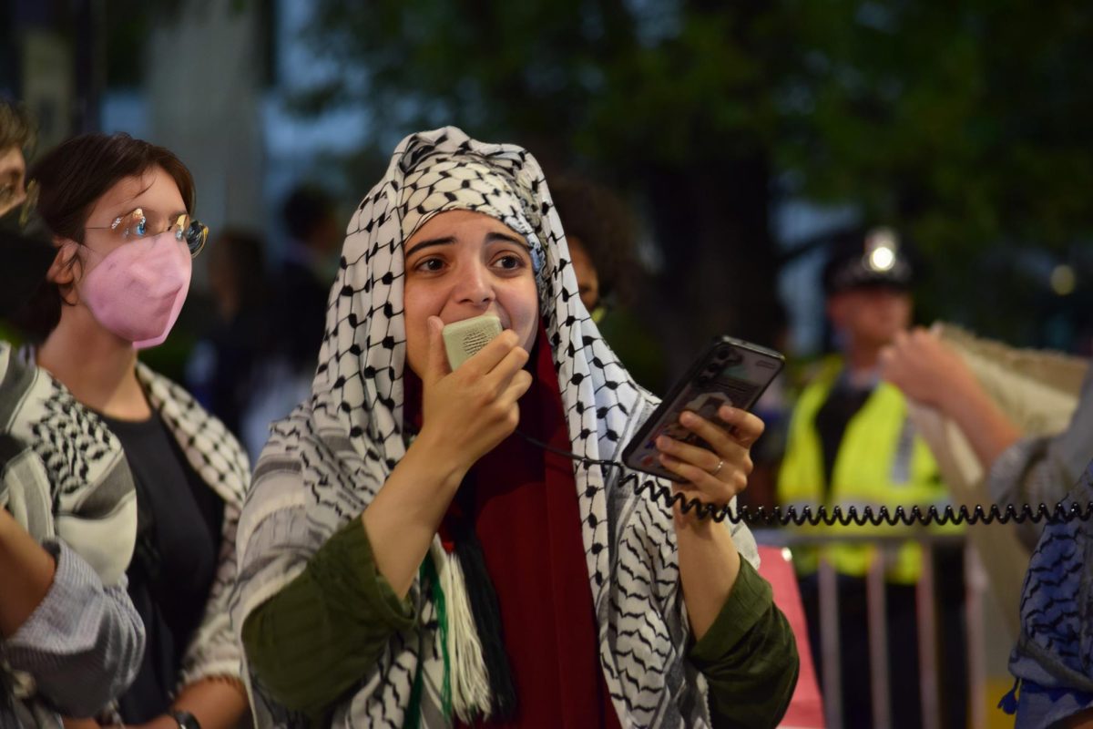 A woman reads names off her phone, saying they belonged to the children who were killed in Palestine this past year. 