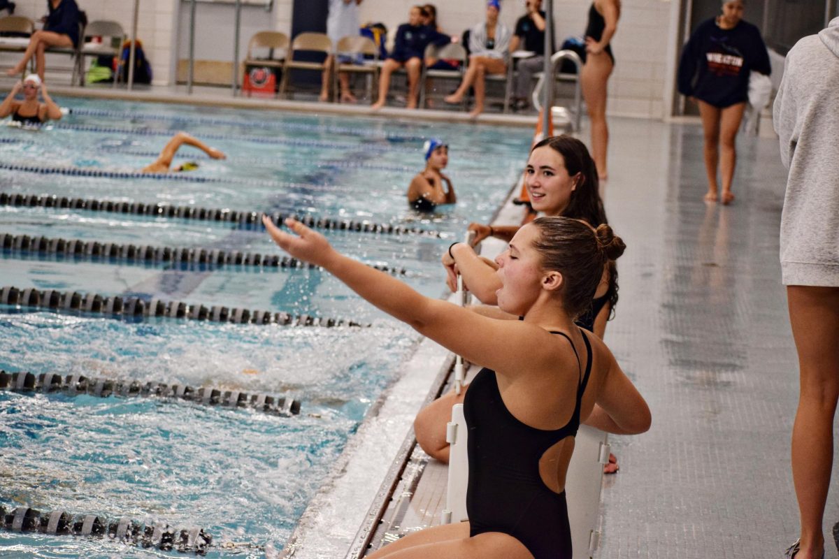 In the 500-free, it can be difficult to keep track of what lap a given swimmer is on, so teammates grab boards that display the number underwater.