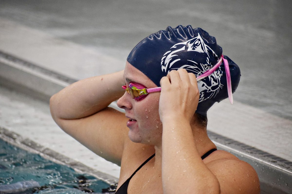 Senior Megan Sego makes a quick goggle adjustment before continuing her warm-up on Sept. 27.