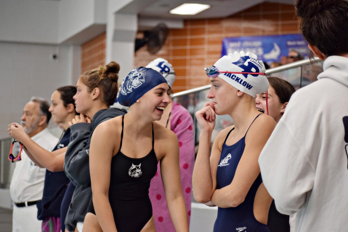 Ava Nelson laughs with a teammate while waiting for the next heat to start. Nelson is a freshman in her first season with the Wildcats.