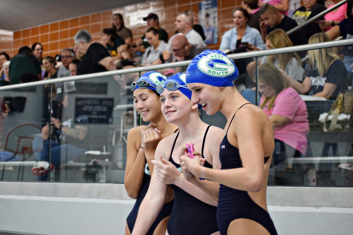 Glenbard West swimmers watch the prelims on Sept. 27 from the pool deck.