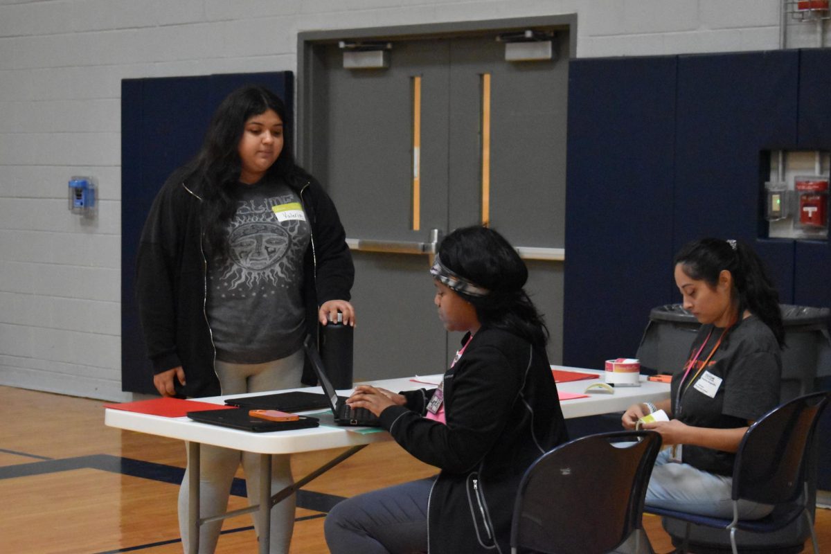 Students  who signed up to give blood check in with the program at the front of the gym setup . 