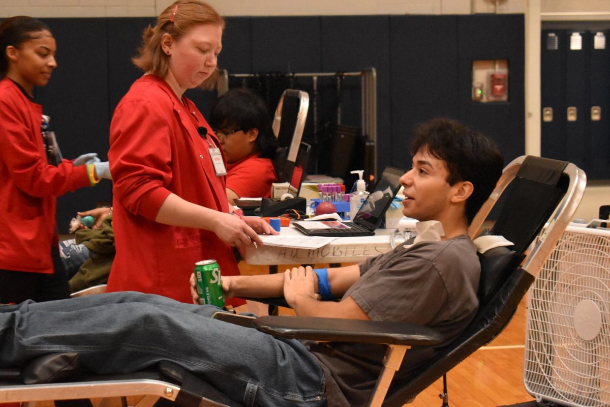 Senior Daniel Guevara talks with a fellow volunteer and drinks a soda, offering insight on his experience. 