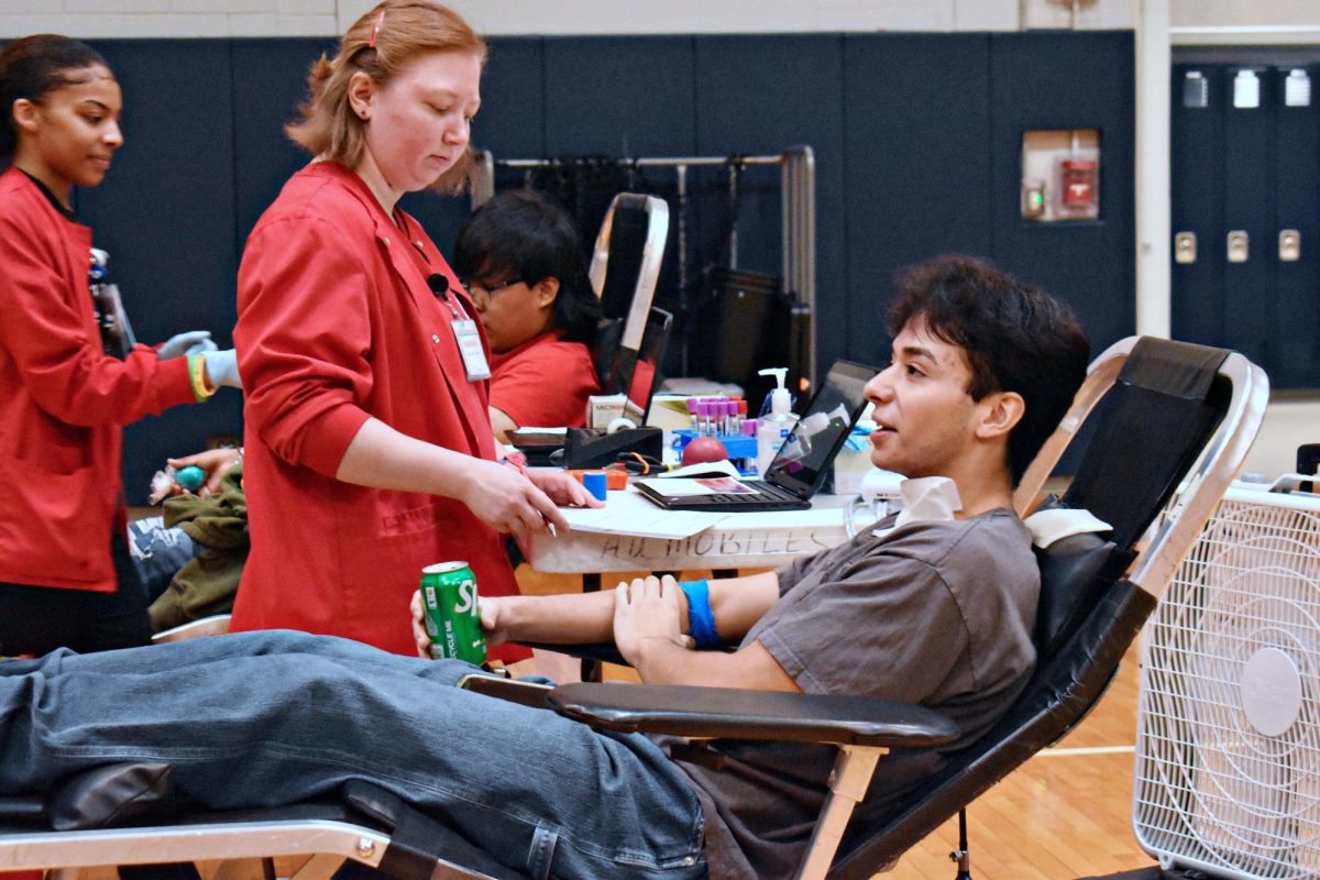 Senior Daniel Guevara talks with a fellow volunteer and drinks a soda after giving blood. It was Guevara's first time donating blood.