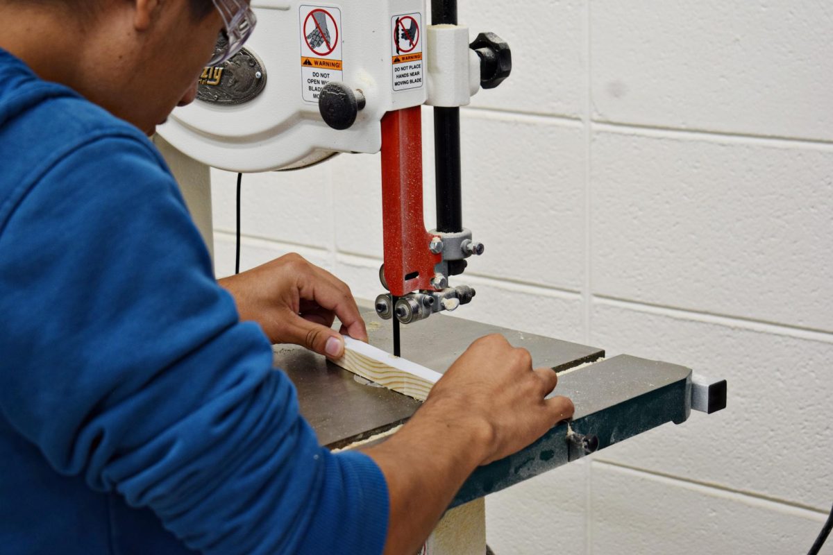 GIC student Christian Herrera, a junior, carefully cuts wood with a bandsaw for an upcoming project. 