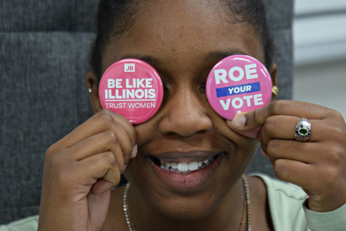 Senior Mariah Varnado holds up two pins distributed by Illinois Democrats and JB for Governer, Political Action Committees in Illinois.