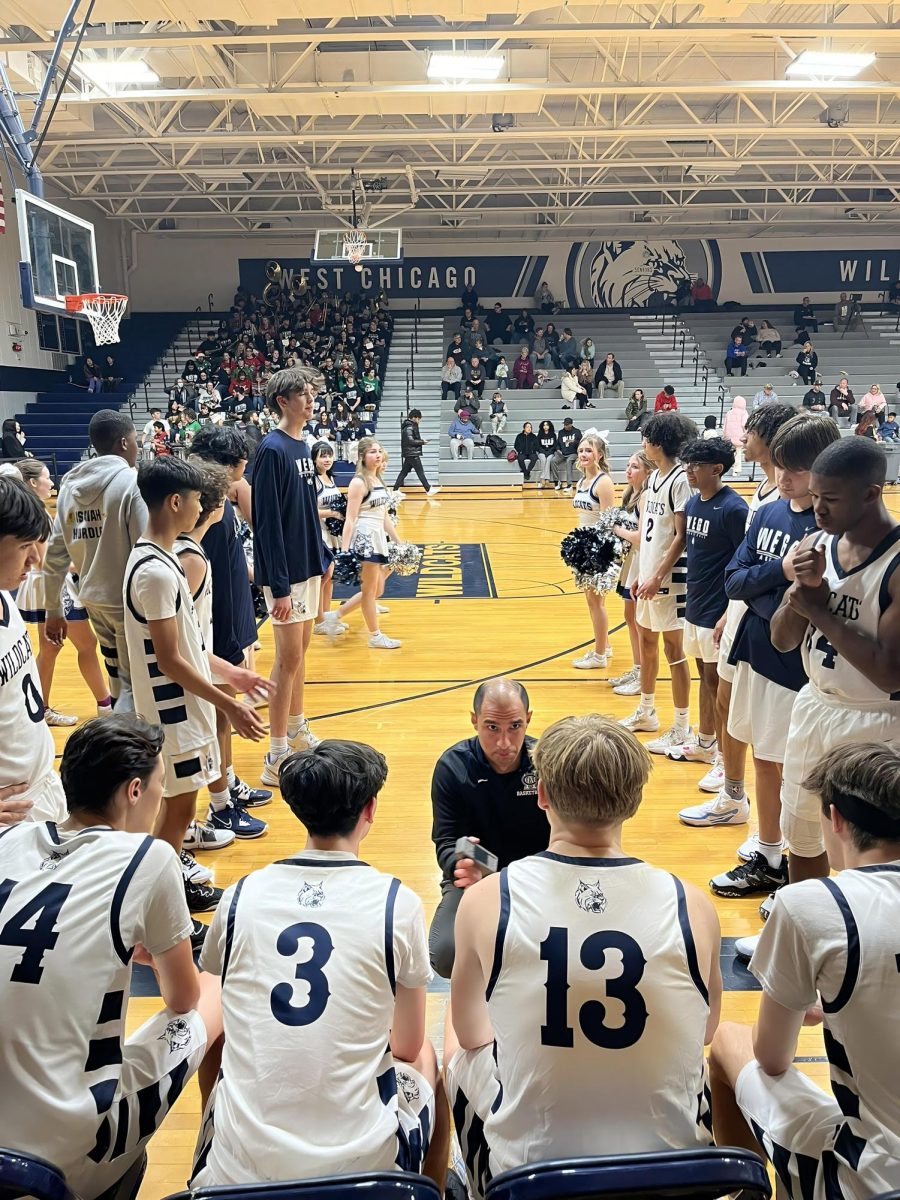 Roy Ramos delivers a pep talk to the Varsity basketball players last season, when he first joined WEGO's staff as a coach. Now, Ramos is working as a dean's assistant as well. (Photo enhanced with AI software to increase resolution; original courtesy of Roy Ramos)