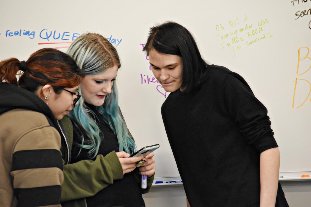 Creative Writing Club members write messages on the whiteboard and check their phones before the adviser come in to the weekly meeting.