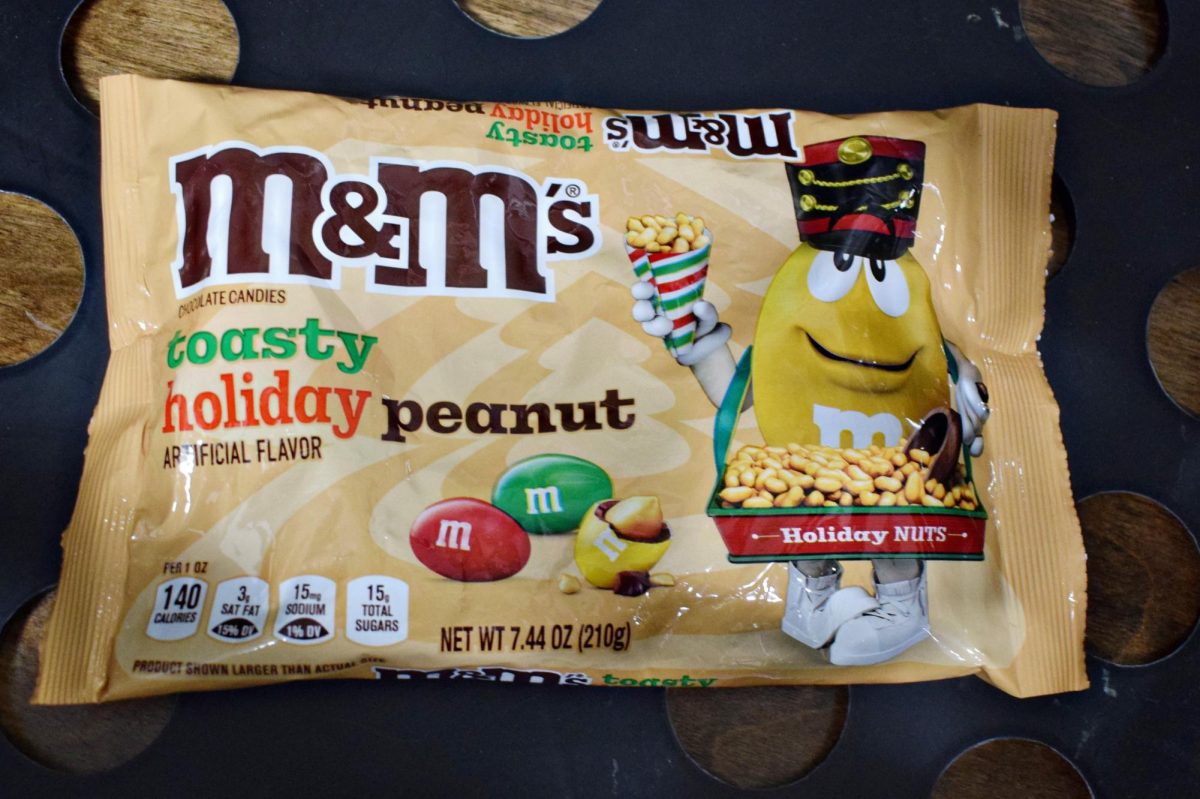 The beige and festive-themed packaging of Toasty Holiday Peanut M&Ms, featuring the Yellow M&M dressed in nutcracker-inspired attire.