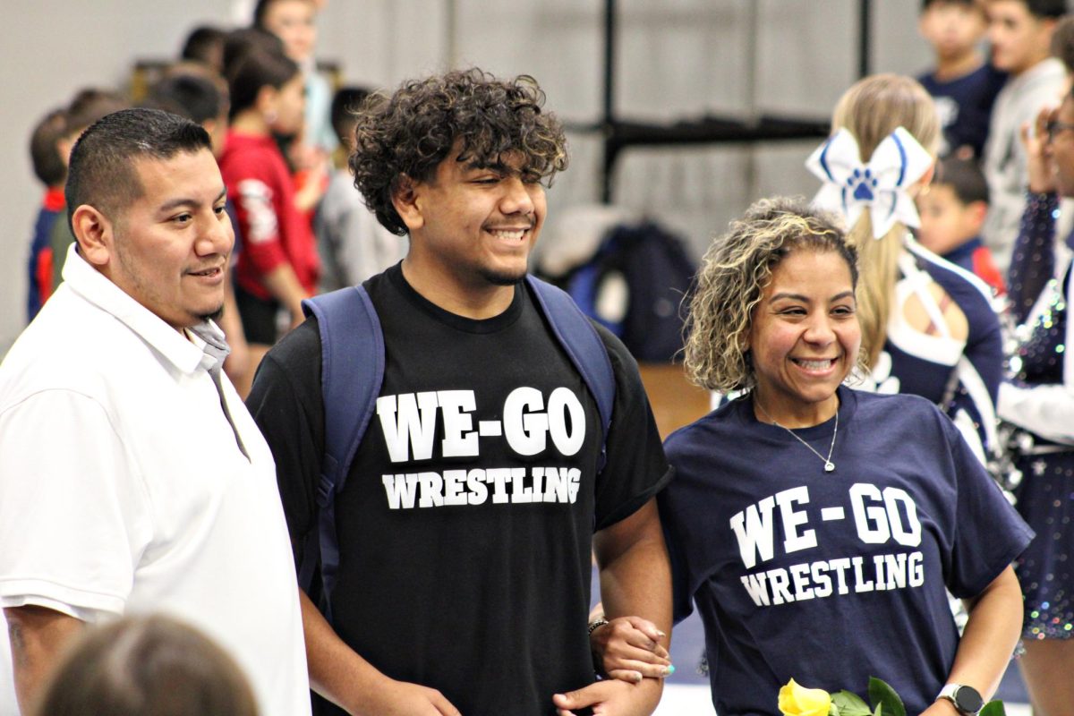 Senior Angelo Jimenez steps out with his parents during the Senior Night meet on Jan. 29 in Bishop Gym. (Photo courtesy of Daisy Fernandez)