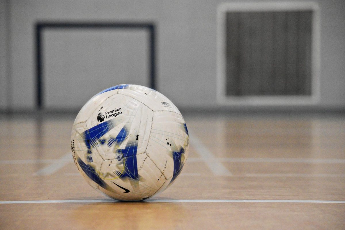 Resting on the gym floor, a well-worn soccer ball awaits the next play, its scuff marks a testament to hours of practice and dedication.