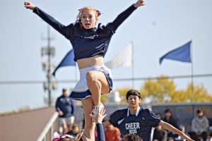 With the support of her bases, junior Julianna Reid balances on one leg during the Homecoming pep assembly in Oct. 2024. 