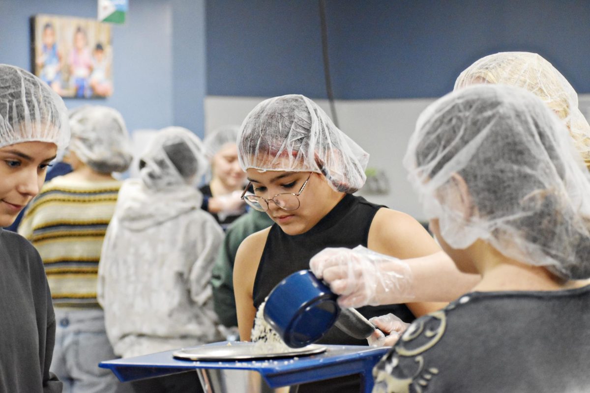 Junior Rowan Canabel-Ferris pours ingredients into the funnel at Feed My Starving Children as part of the EPIC event organized by Mark Poulterer. Canabel-Ferris attended with Creative Writing Club.