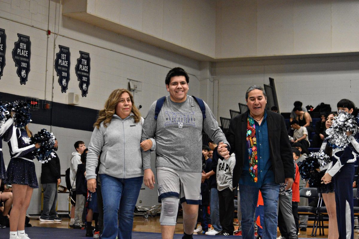 Senior Omar Sarmiento, who suffered an injury earlier in the season, beamed as he walked out with his parents during West Chicago's Senior Night on Jan. 29 in Bishop Gym. Despite his setback, Omar competed in the Upstate 8 Conference on Jan. 25, demonstrating resilience and dedication to his team.