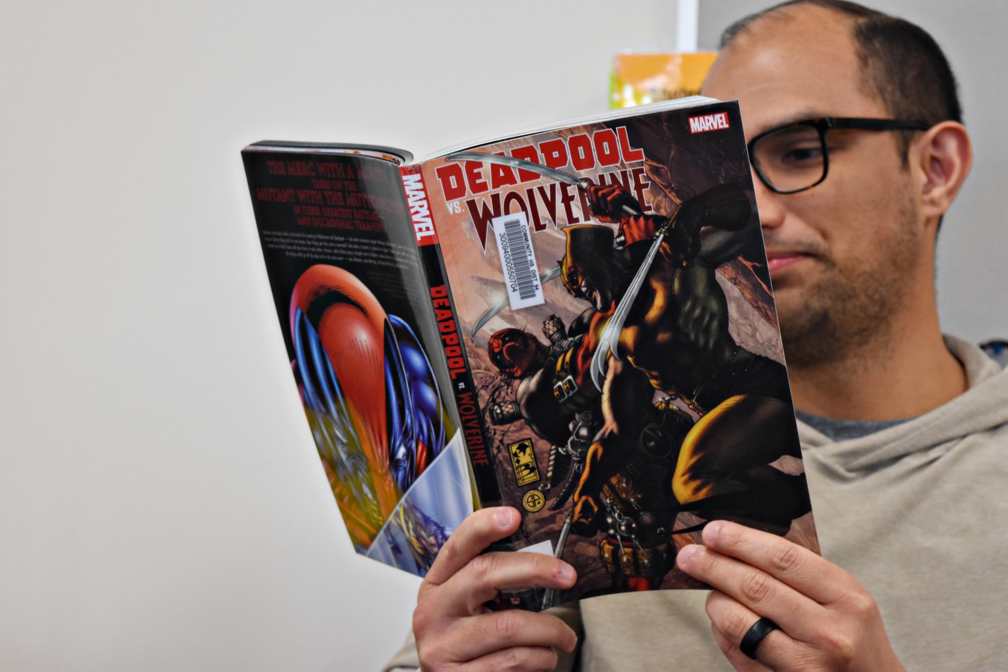 Roy Ramos, Dean's Assistant at West Chicago Community High School, reads "Deadpool vs. Wolverine" in the study hall room. Marvel’s latest comic releases, including Ultimate Wolverine, continue to fuel the ongoing debate between Marvel and DC fans. 