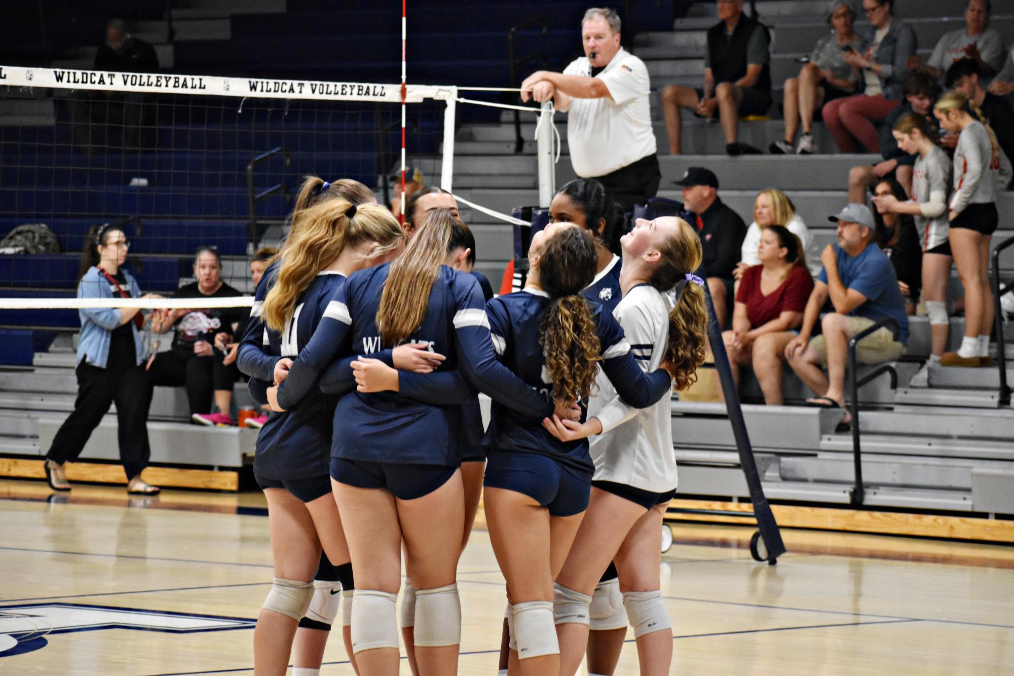 The Wildcats huddle together between points during their match against Palatine on Aug. 27 at West Chicago Community High School.