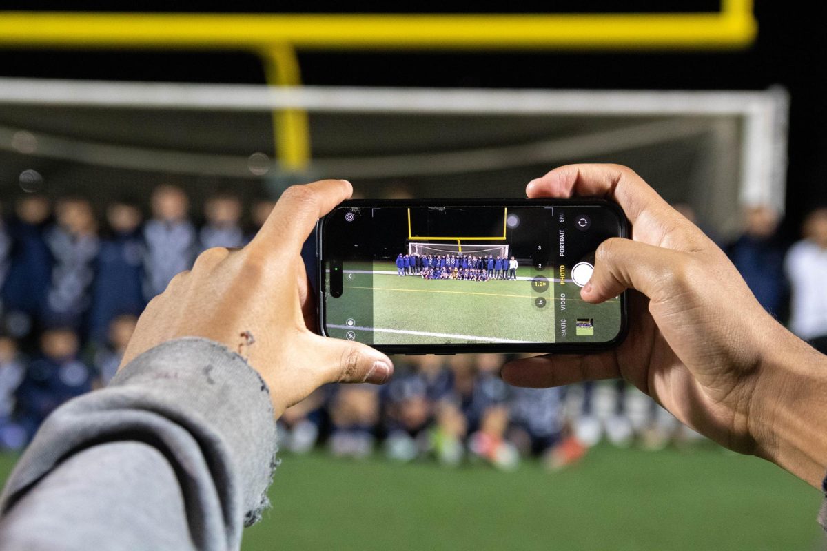 A spectator takes picture off their phone of the West Chicago Community High School Varsity soccer team after they won the regional championship on Oct. 24, 2025.