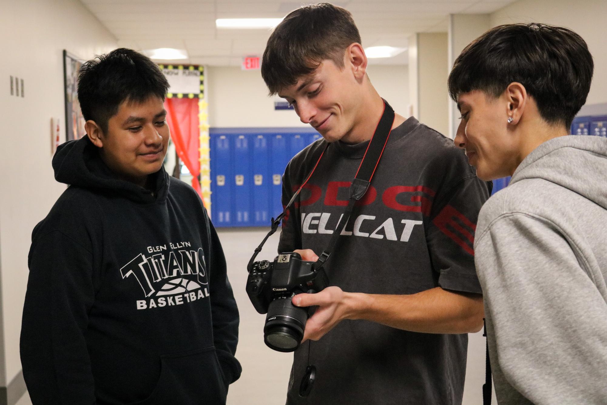 West Chicago Community High School senior Sean Blickhan shows off a photo to his two classmates on a DSLR.