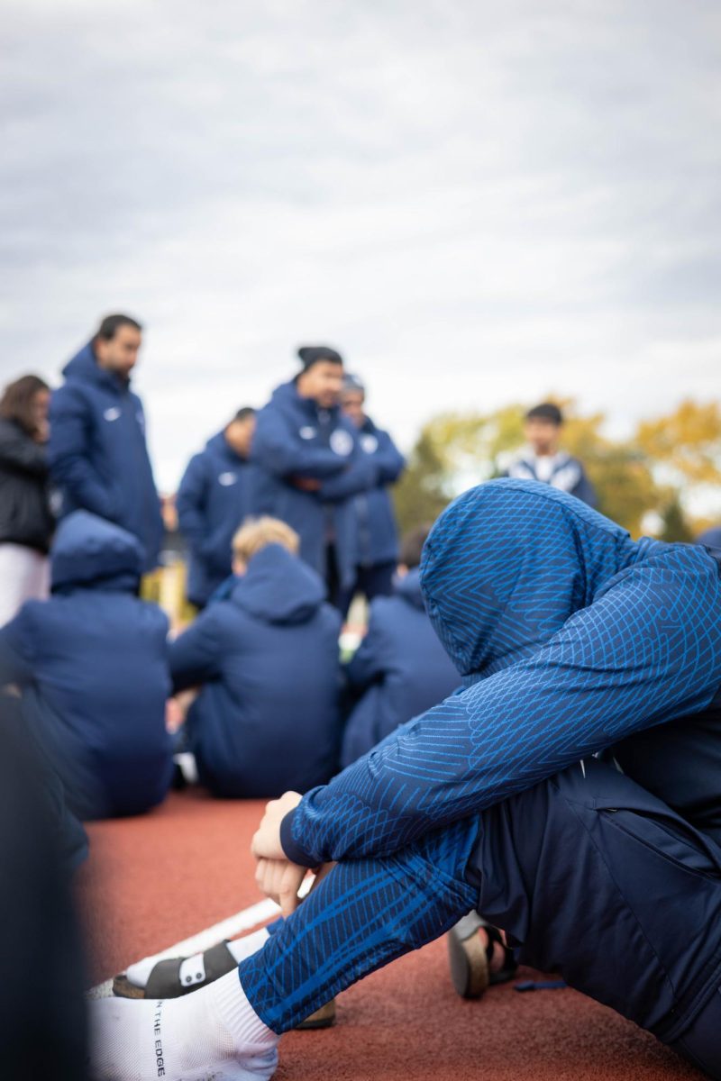 A Wildcat boys soccer player grieves a playoff loss while assistant coach Dorian Carrasco speaks to the team.