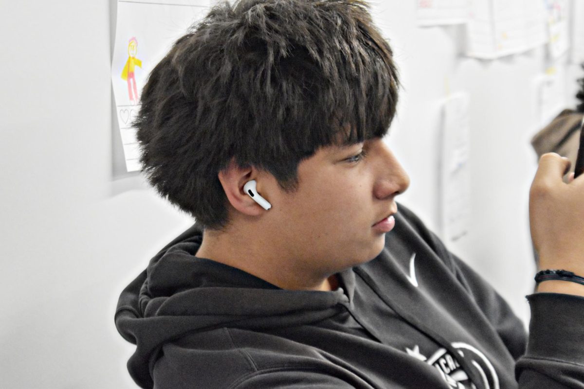 Senior Julien Robles listening to music with his Airpods in as he scrolls during class.