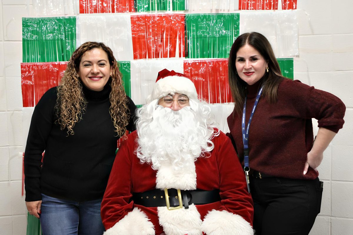 BPAC president Liliana Medina and Family Outreach Coordinator Teresa Ocon gather to take a photo with Santa Claus during the posada held on Dec. 13 at West Chicago Community High School.