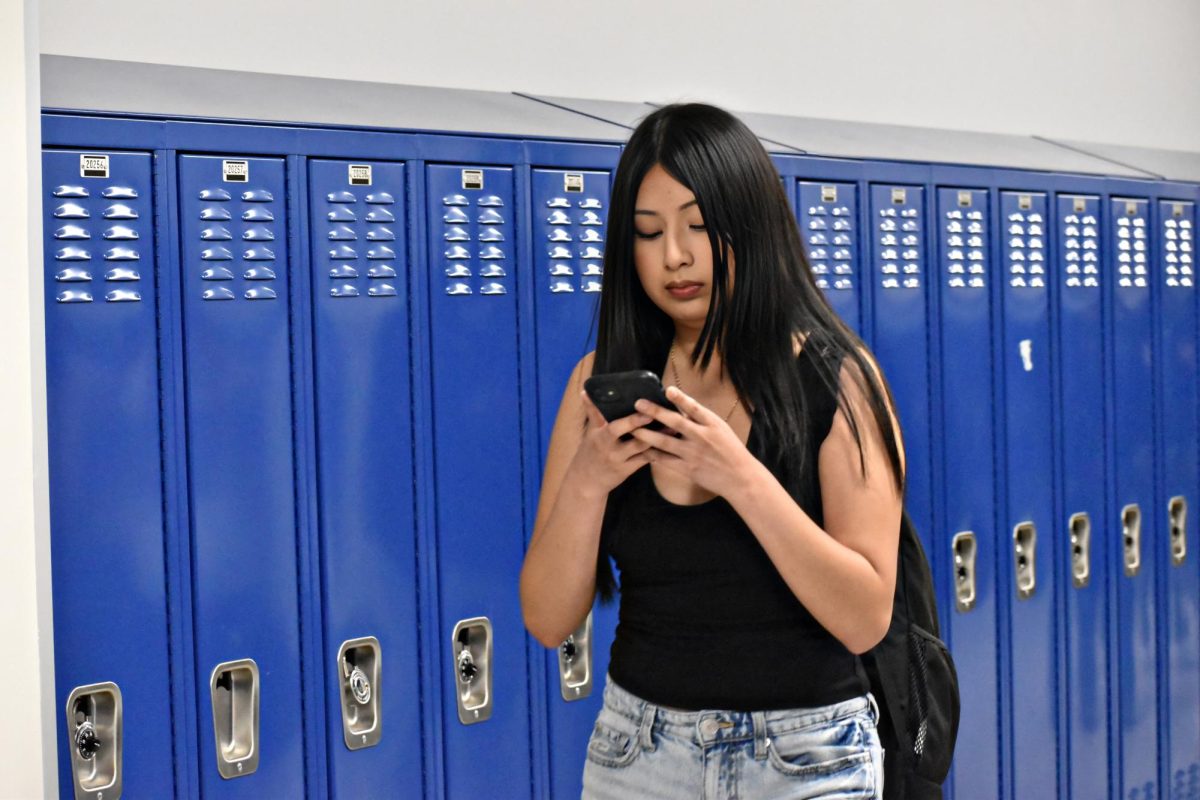 A West Chicago Community High School student checks her phone during the passing period. 