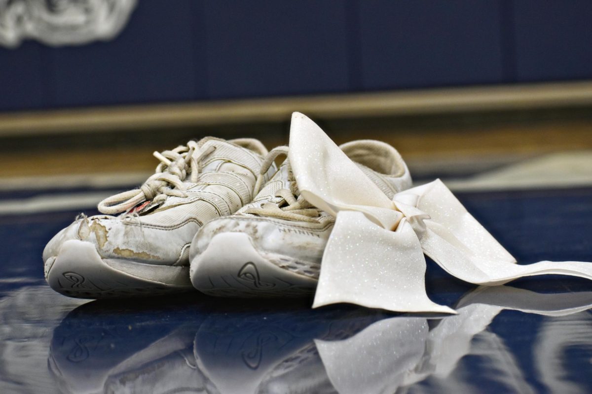 Worn out cheer shoes and a sparkly bow lay on the floor of Bishop Gym. The team competed at Oswego High School this past weekend, hoping for a state bid.