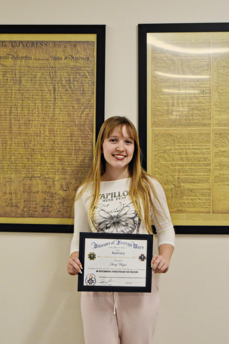 Avery Unger holding her first place certificate for the VOD competition in the humanities hallway. 