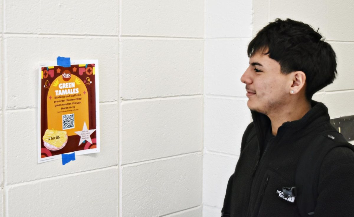 Junior Martin Vargas reads an NHS tamale fundraiser flyer near the history hallway. The sale aims to raise funds for this year's and future NHS events and conferences.